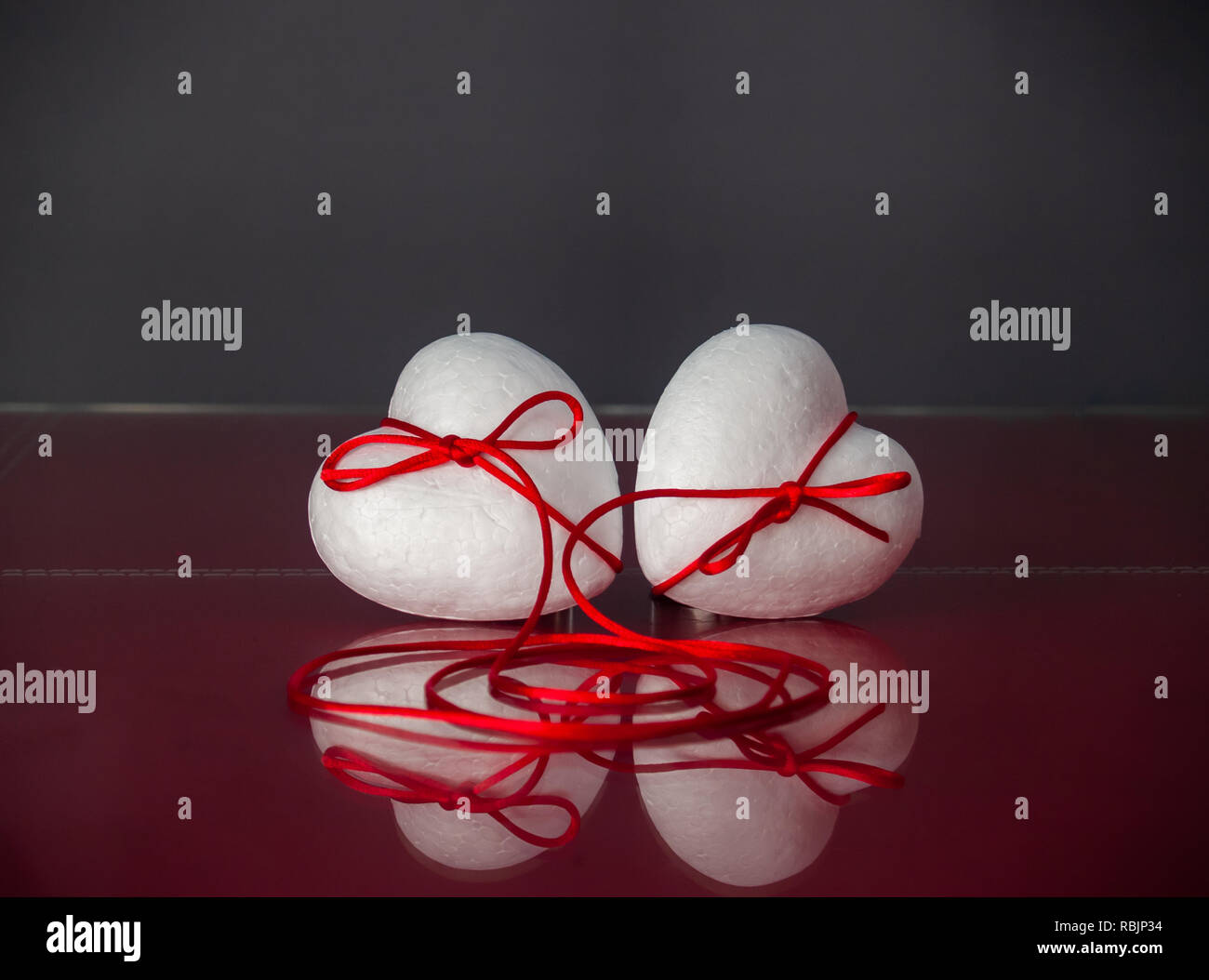 Concept of love Two poliespan hearts joined with a red thread that ...