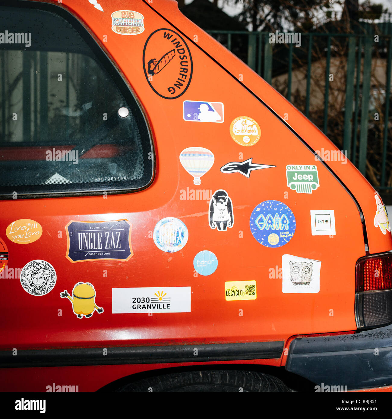 Strasbourg, France - Jan 1, 2019: Side view of red vintage Peugeot car with multiple stickers from know cartoon to diverse brands  Stock Photo