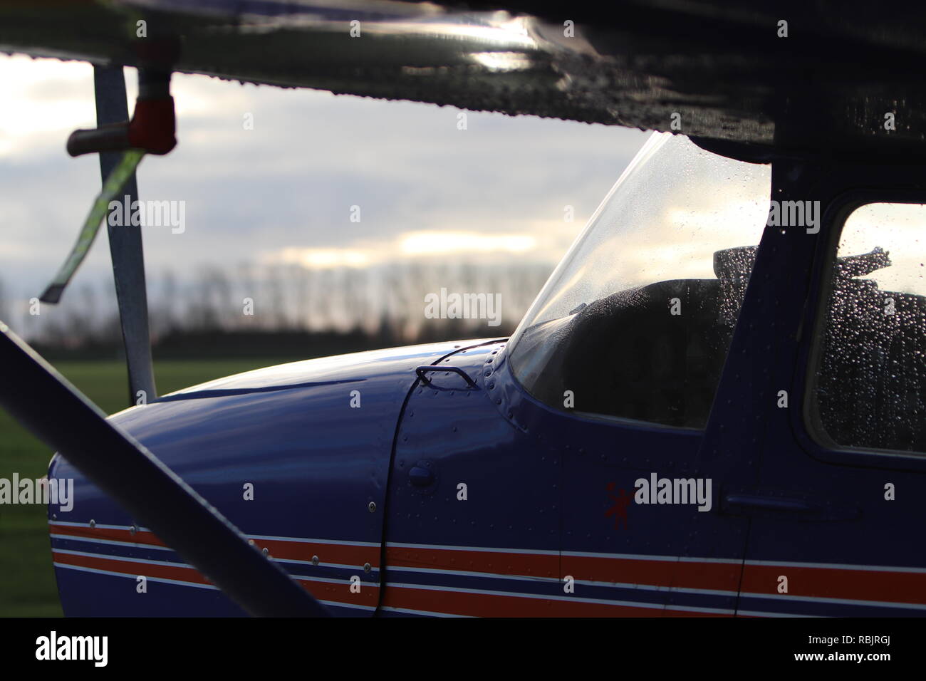 A Cessna 172 sits on the airfield in a dusky glow, fresh from the rain... Stock Photo