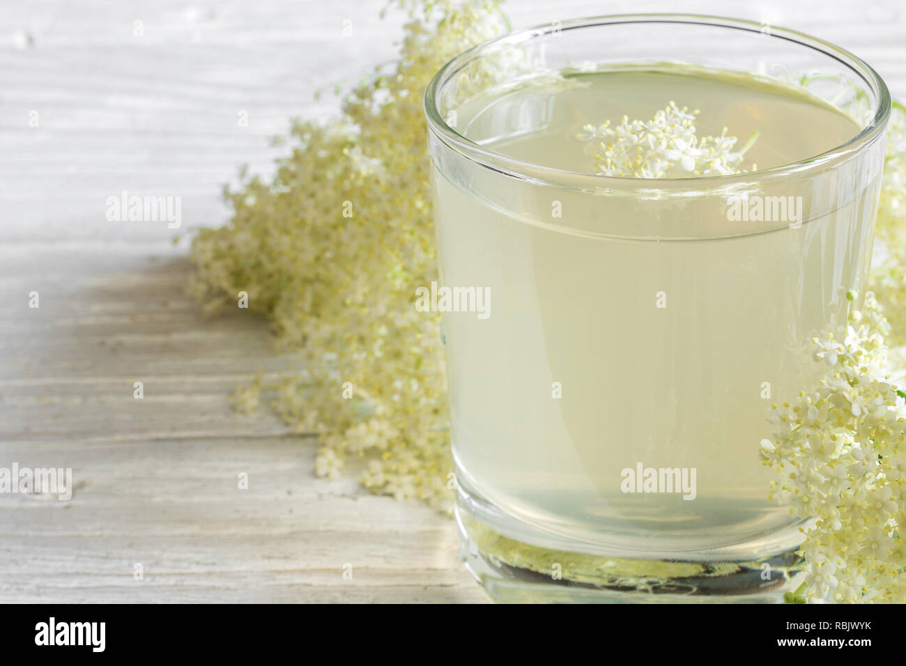 homemade elder flower syrup with flowers on white wooden table. healthy herbal drink. close up Stock Photo