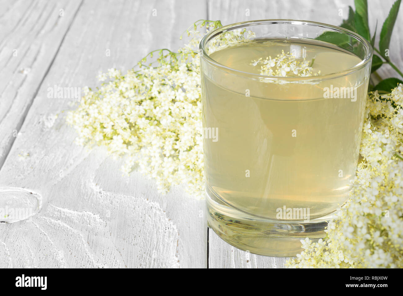 Elderflower syrup with flowers on white wooden table. healthy herbal drink. close up Stock Photo