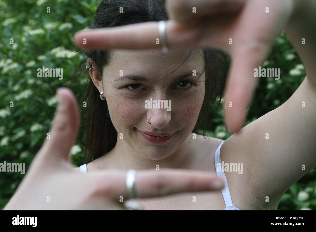 Brunette girl in a park outdoors on a sunny day giving hand signals Stock Photo