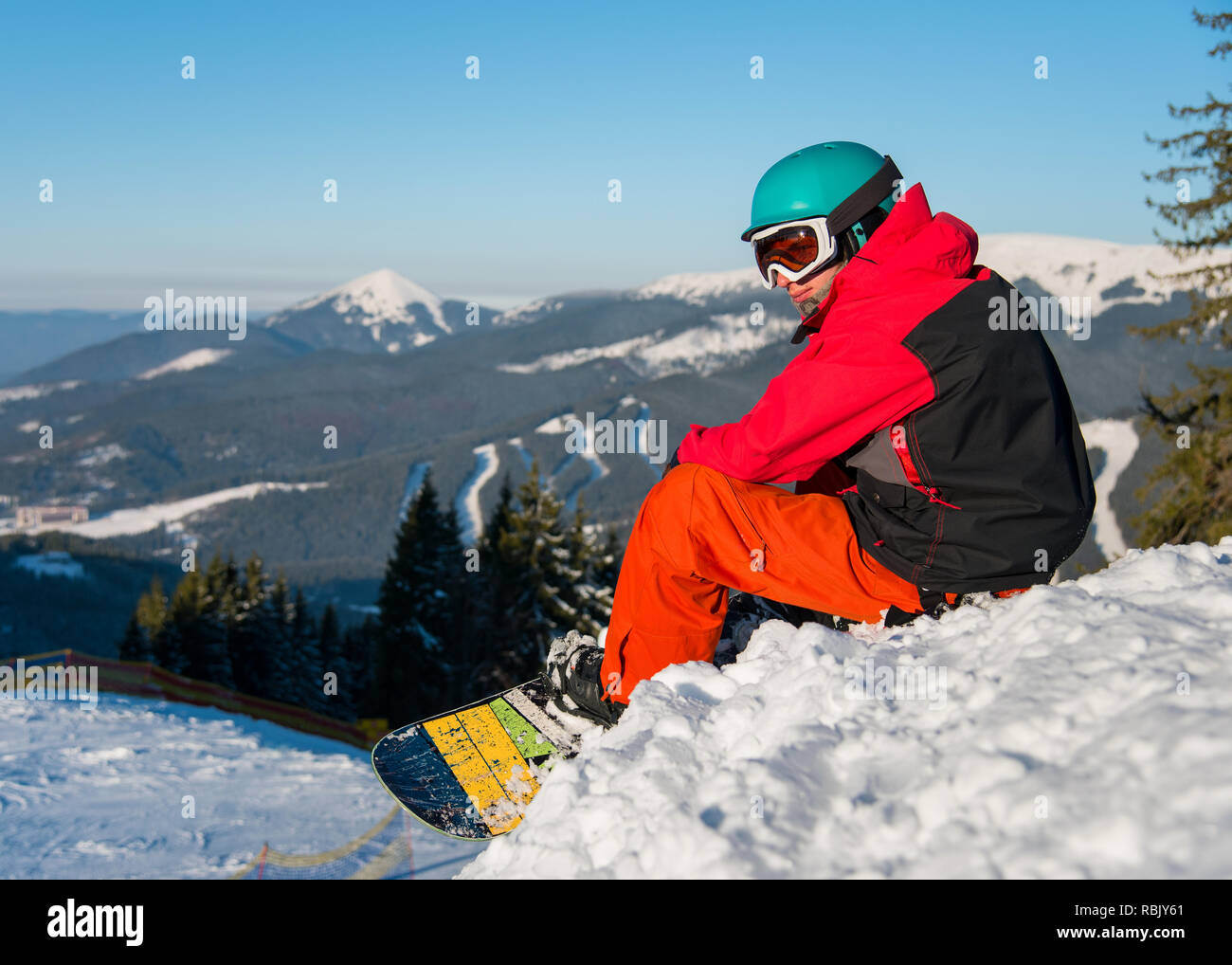 Shot of a snowboarder enjoying beautiful view of snowy mountains, winter ski resort, relaxing on the edge of a slope looking around copyspace recreation travelling tourism. Stock Photo