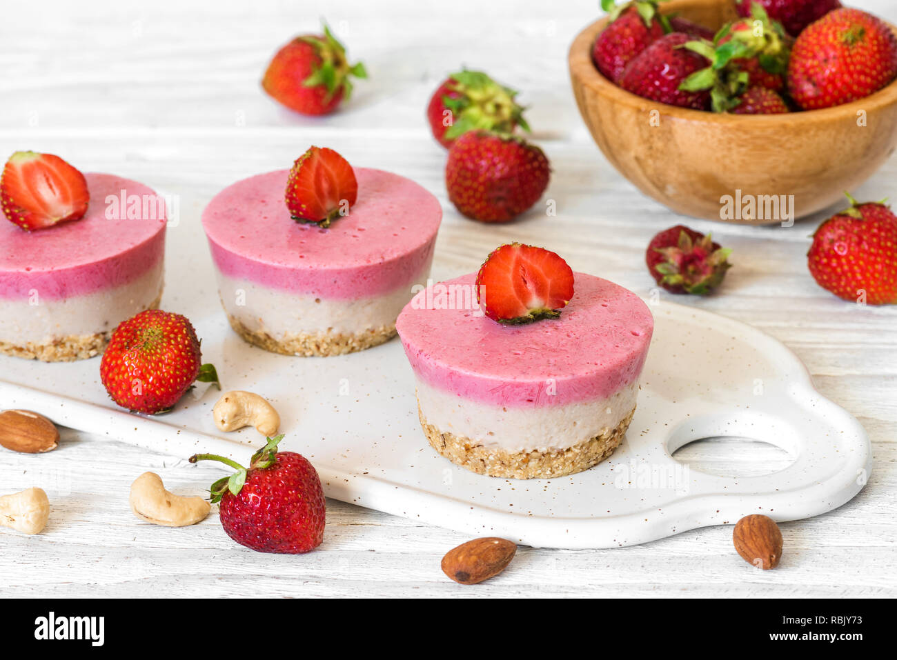 vegan raw strawberry and banana cakes with fresh berries and nuts. healthy delicious food Stock Photo