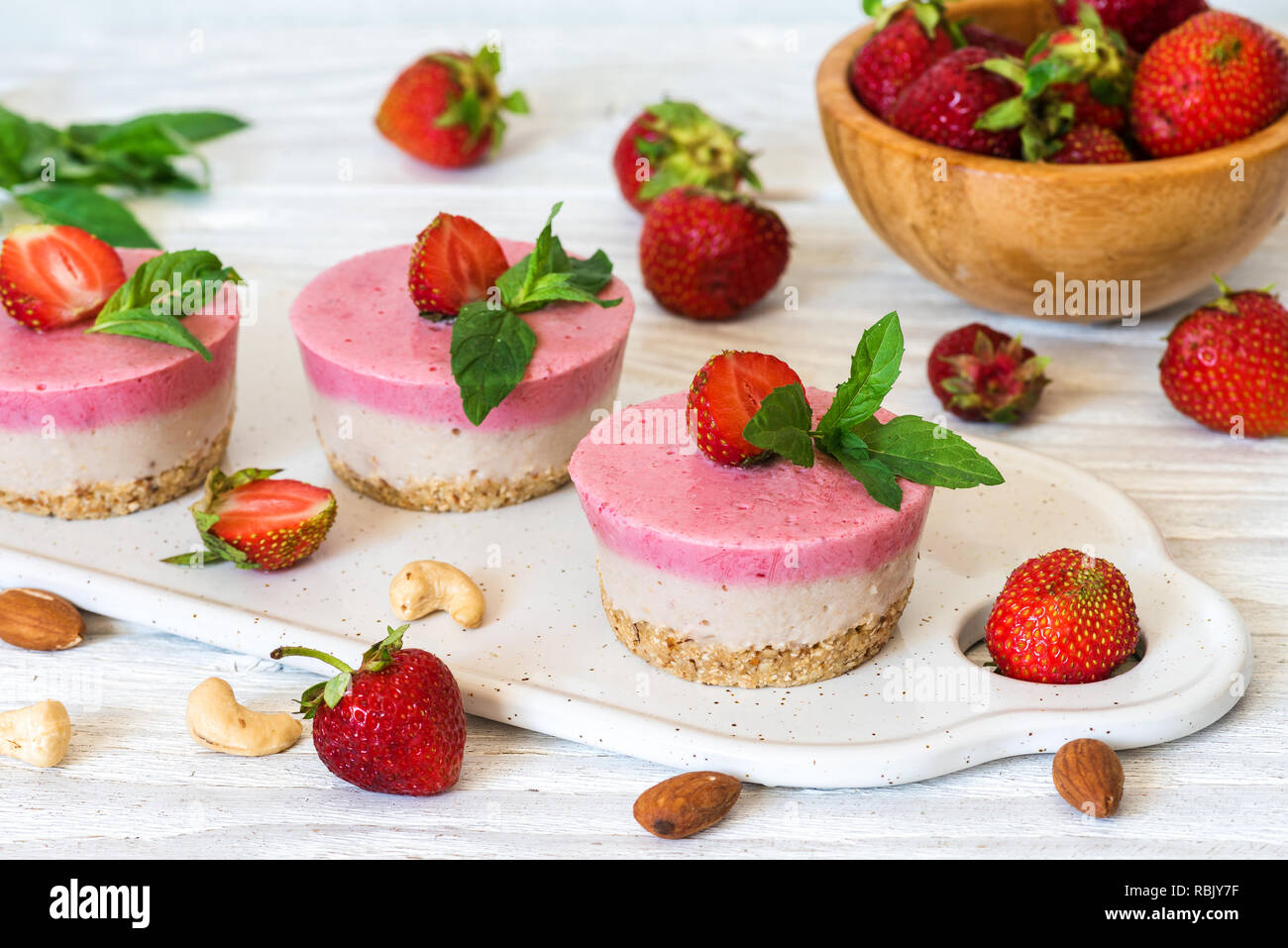 vegan raw strawberry and banana cakes with fresh berries, mint and nuts. healthy delicious food Stock Photo