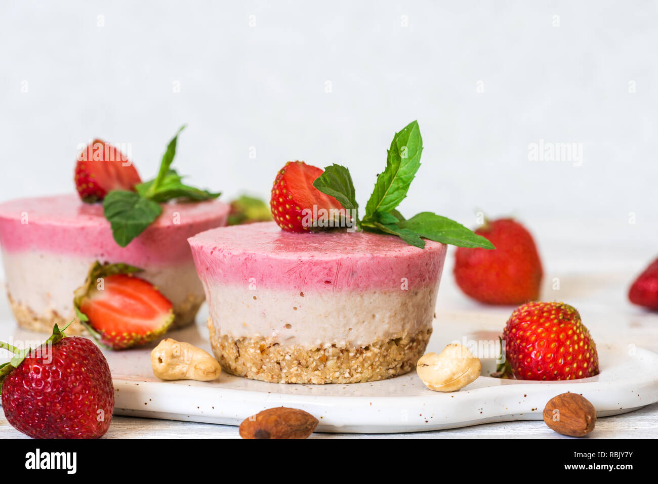 vegan raw strawberry and banana cakes with fresh berries, mint and nuts. healthy delicious food. close up Stock Photo