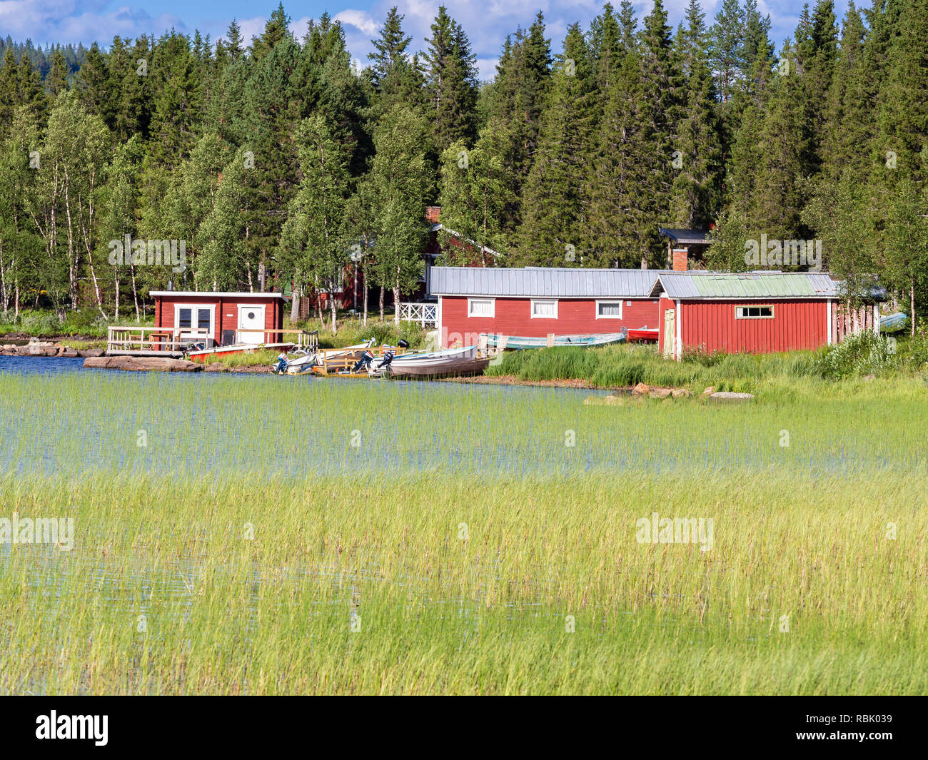 Typical red houses and boat sheds at a lake west of Kiruna, reed growing at the shore, Kiruna, Sweden Stock Photo