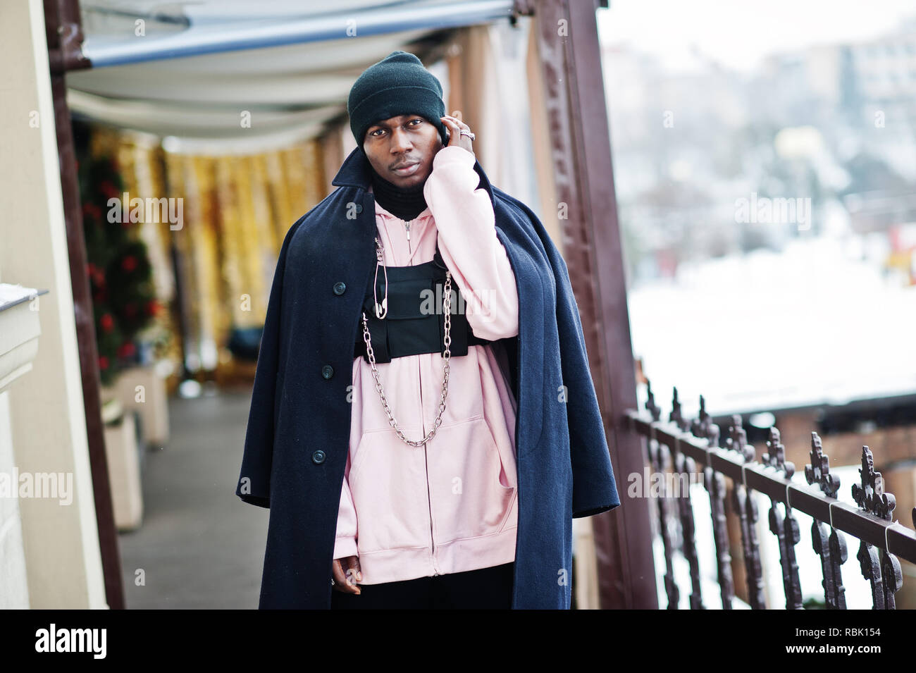 Stylish urban style african american man in black coat and hat, pink hoodie  posed at winter day Stock Photo - Alamy