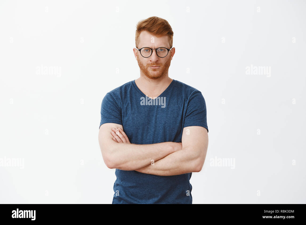 Strict european redhead male teacher being angry at student failing exam. Portrait of serious-looking handsome mature male with bristle in cool glasses, staring at camera, crossing fingers on chest Stock Photo