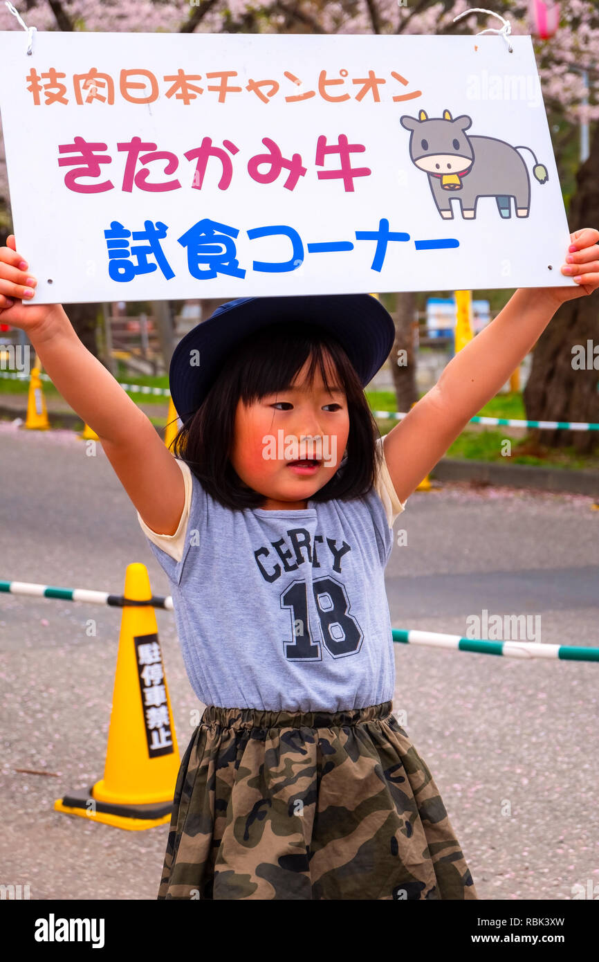 Iwate , Japan - April 22 2018: Unidentified young Japanese girl holds sign selling the Kitakami beef for tourist during the full bloom cherry blossoms Stock Photo