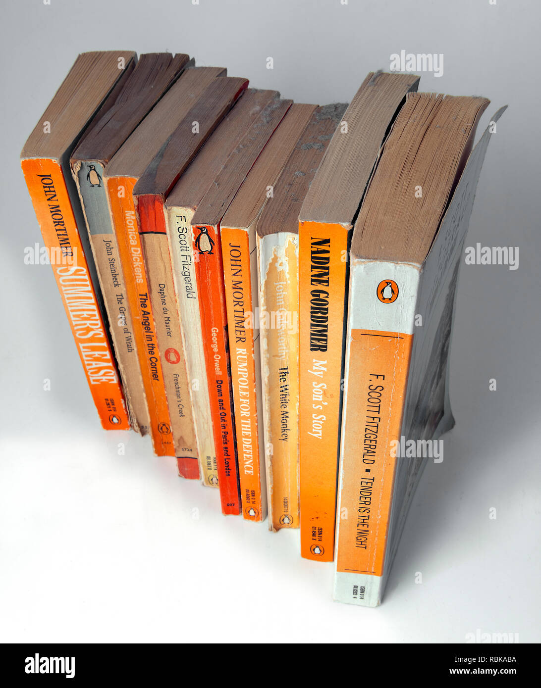 Collection of Penguin paper back books gathering dust from being left on a book shelf  for 20 years . Stock Photo