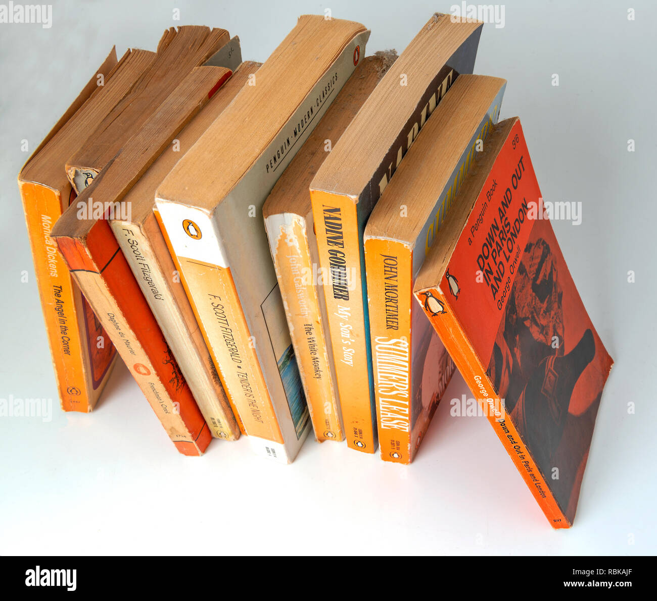 Collection of Penguin paper back books gathering dust from being left on a book shelf  for 20 years . Stock Photo