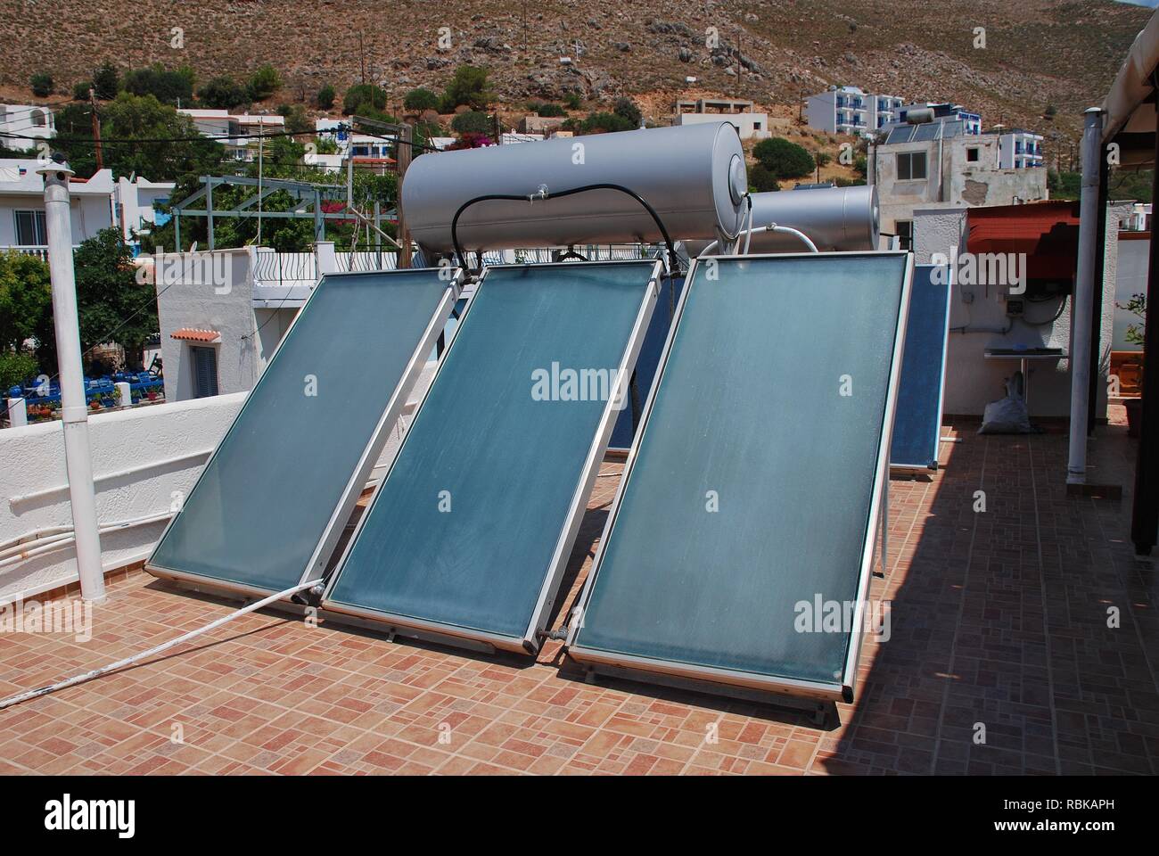 A bank of solar heating panels on a roof top in Livadia on the Greek island of Tilos on June 21, 2018. Stock Photo