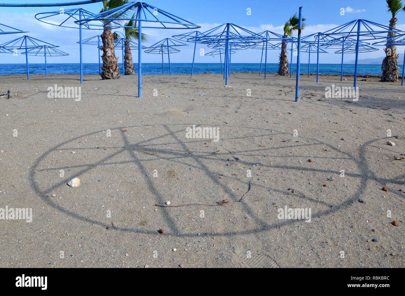Shade of a parasol frame on a beach near the little village (Limenas