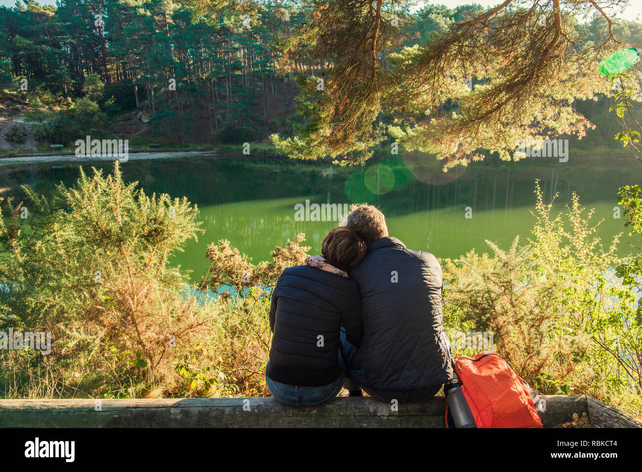 Back view of lovely couple man and woman sitting near forest lake ...