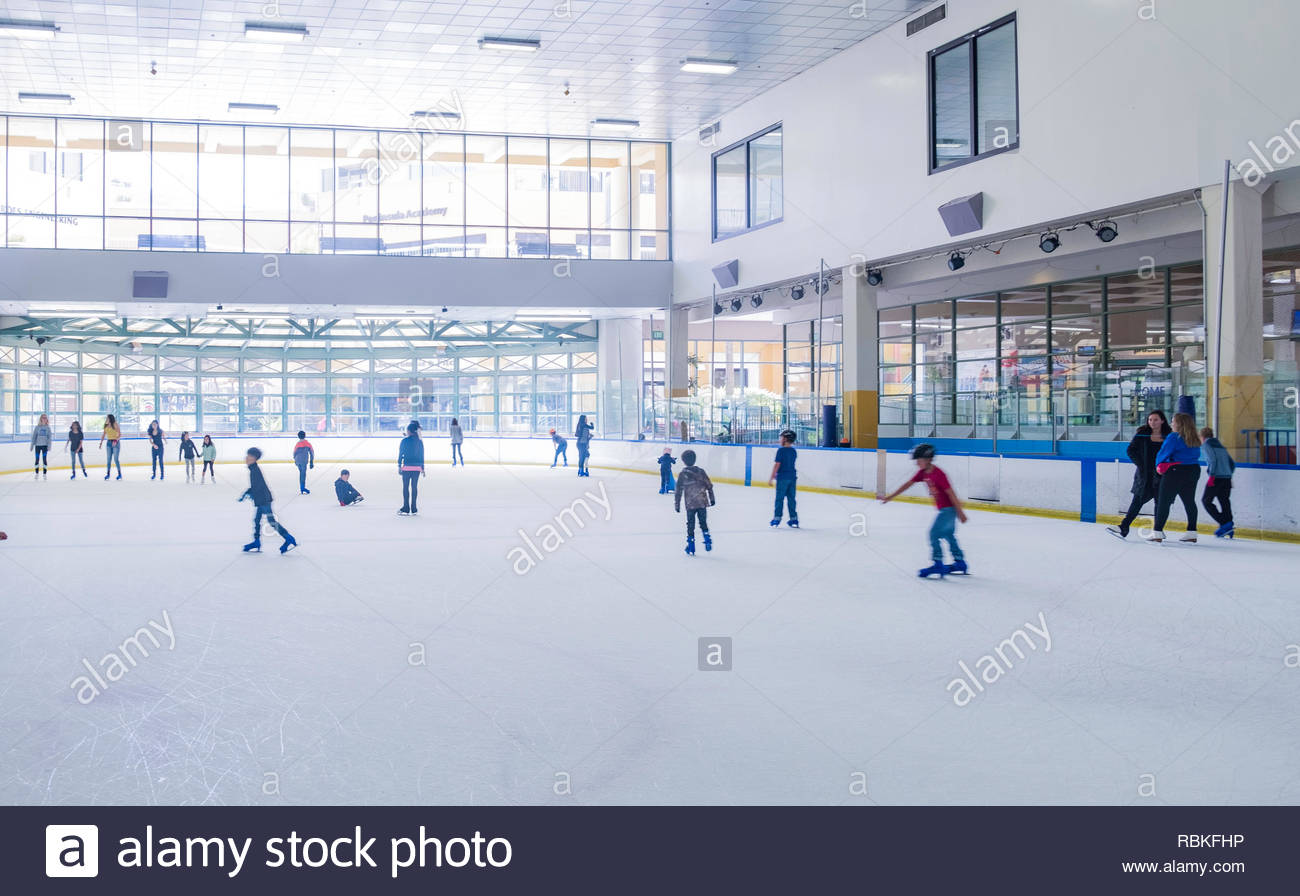 Adults and children ice skating inside 