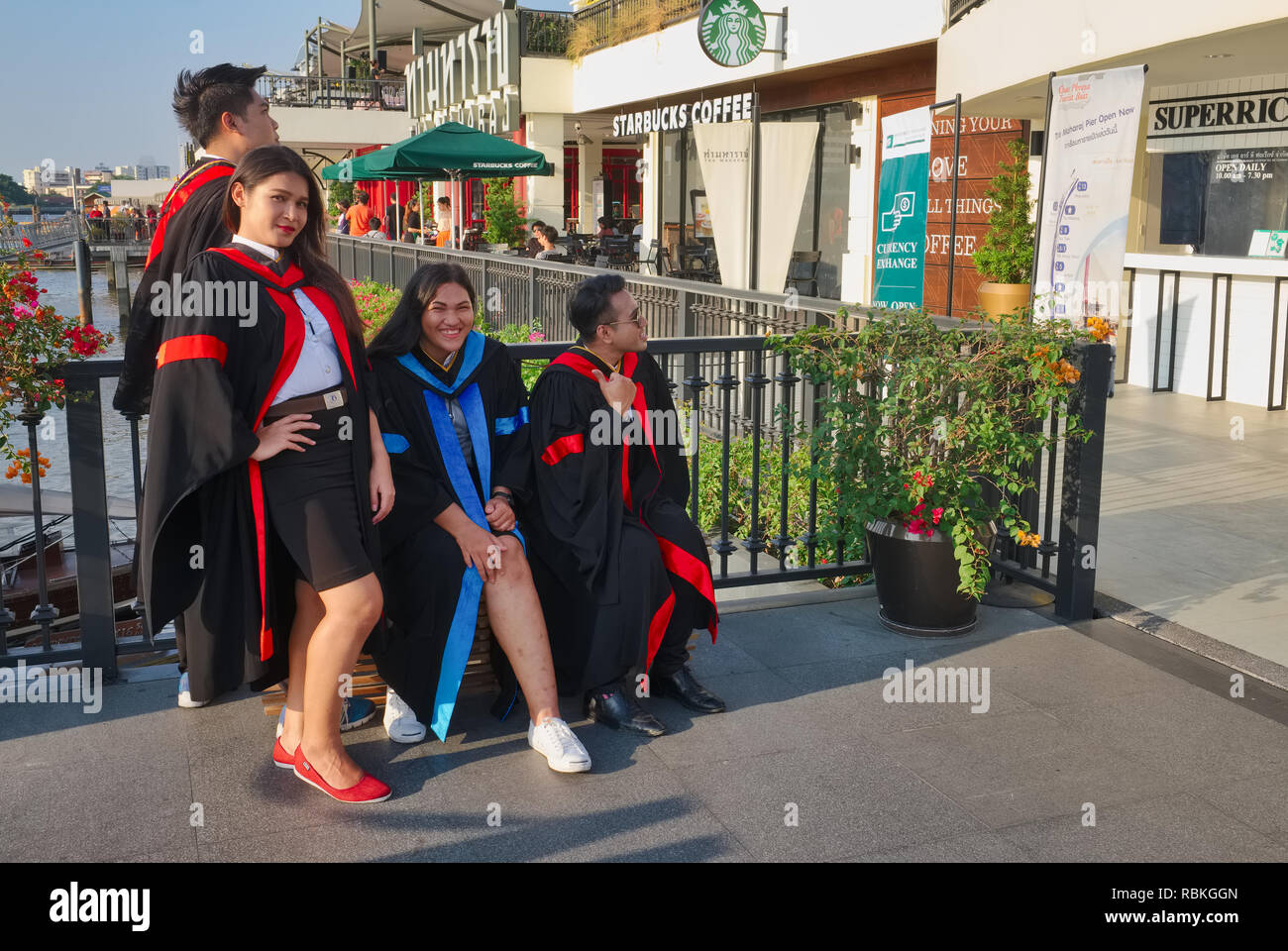 Students of Thammasat University, Bangkok, Thailand, posing for photos after graduation; in front of a Starbucks at Maharaj (Maharat) Pier, Bangkok Stock Photo
