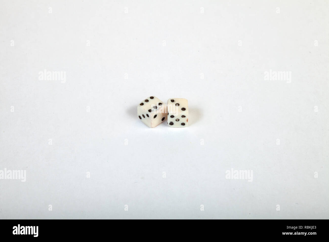 Two very small dice near each other on a large white isolated