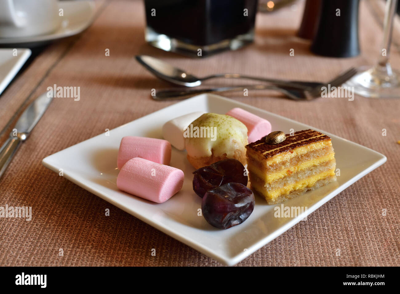 Set of sweets on white plate on table in cafe Stock Photo