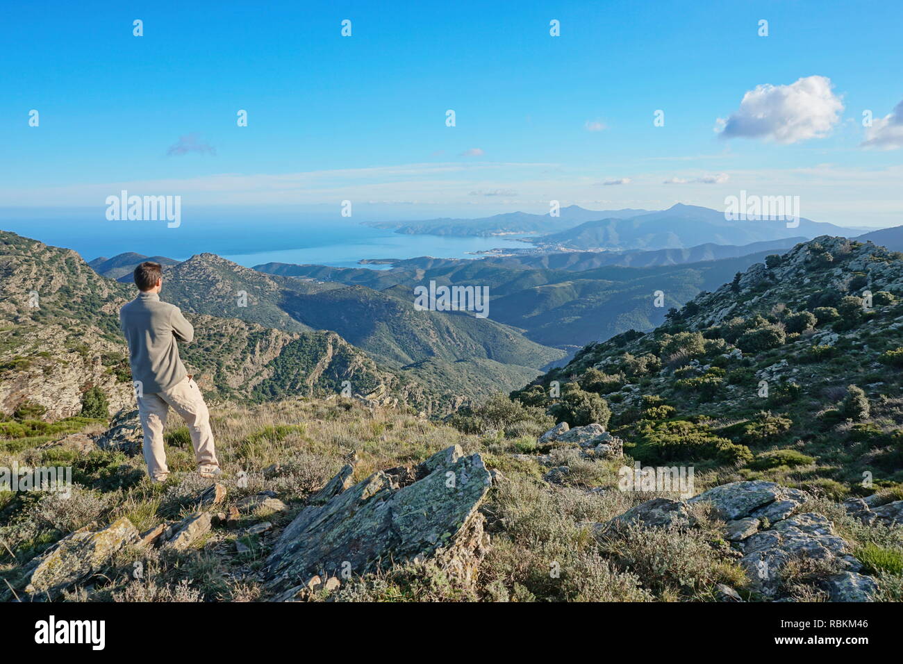 Spain landscape a man standing looking at view from the Albera mountain with the Mediterranean sea and Cap de Creus in background, Pyrenees, Catalonia Stock Photo