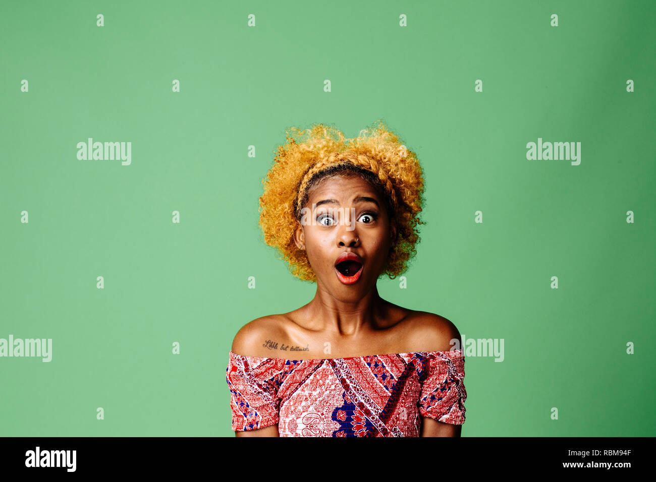 Young woman with a shocked expression looking at something, isolated on green studio background Stock Photo