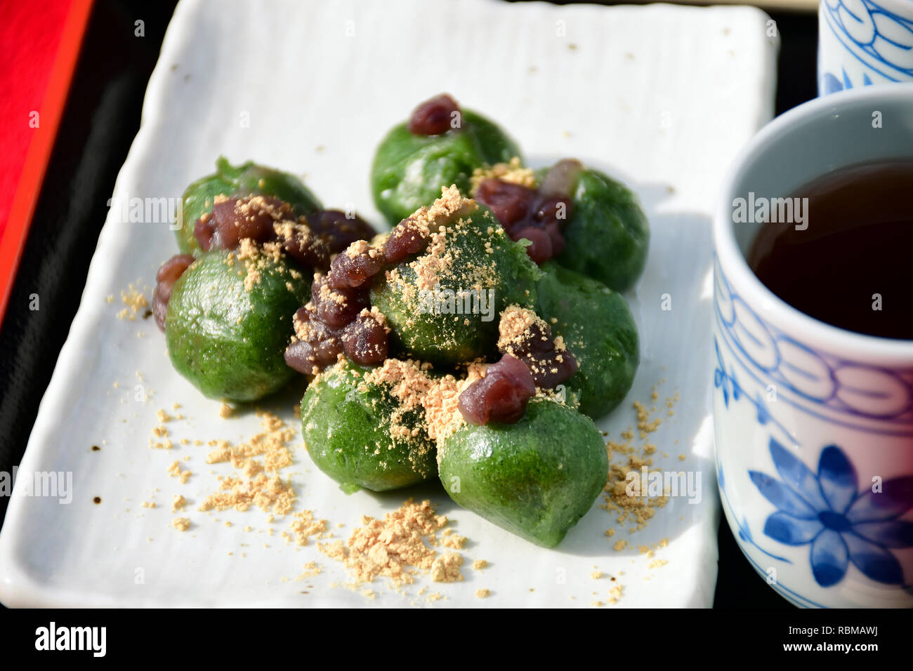 Japanese Dango, Japanese Traditional Sweets. Dango green tea dumplings flavors topping with red bean paste (anko) served with hot tea. Stock Photo