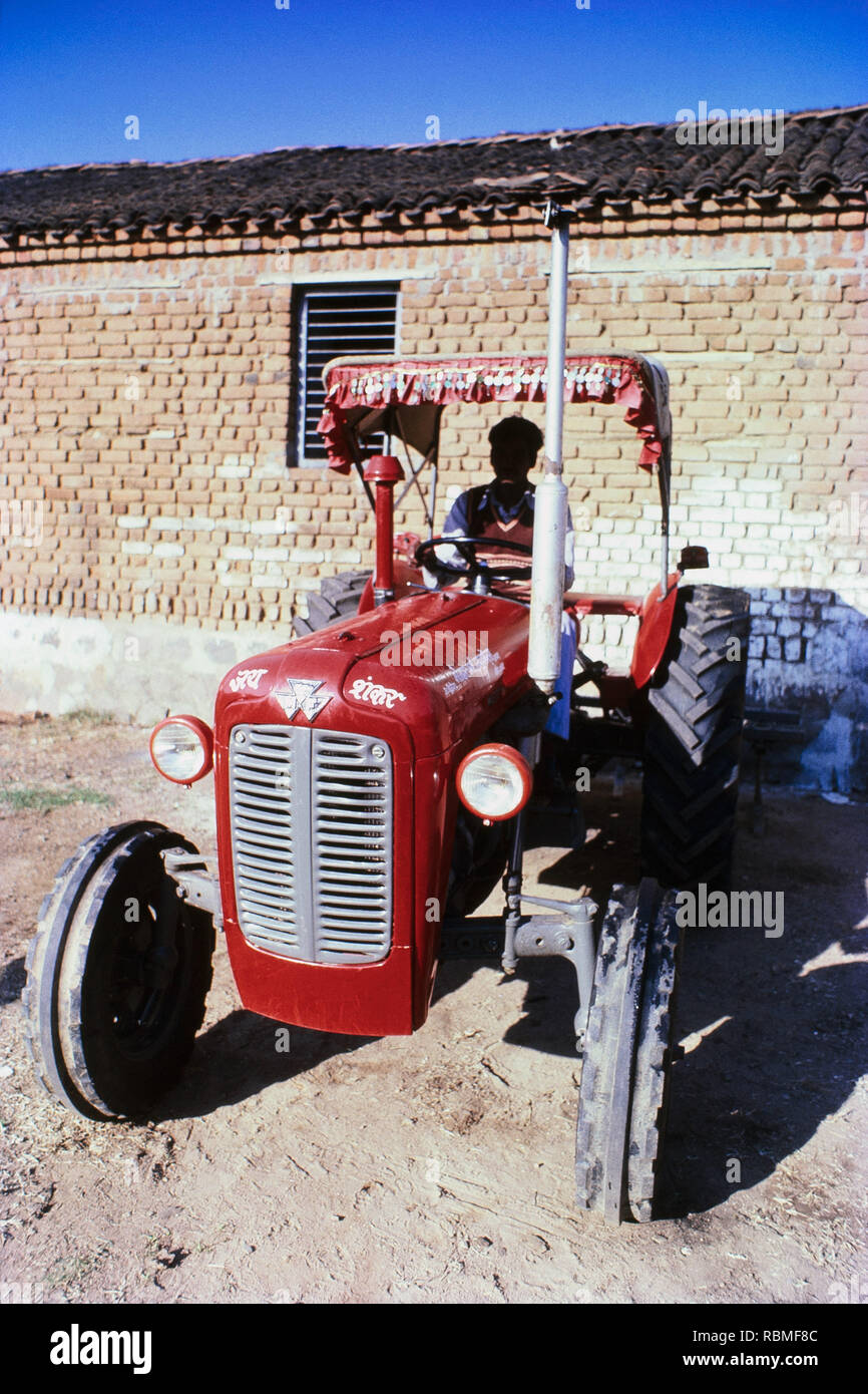 Red colour tractor parked in front of brick wall, India, Asia Stock Photo
