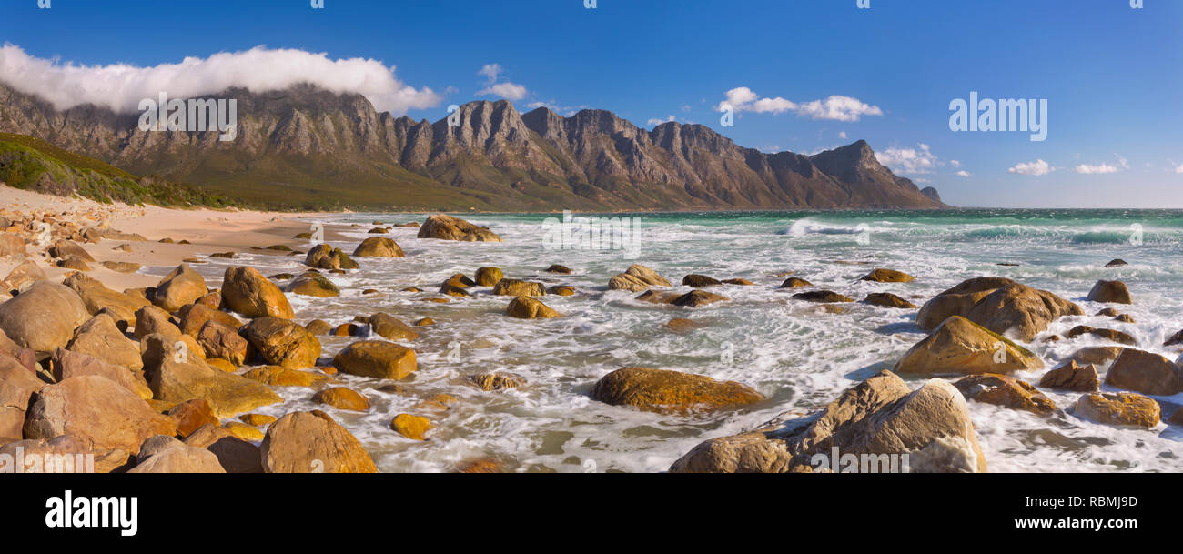 A rocky beach at the Kogel Bay in South Africa with the Kogelberg Mountains in the back. Photographed on a very windy but sunny day. Stock Photo