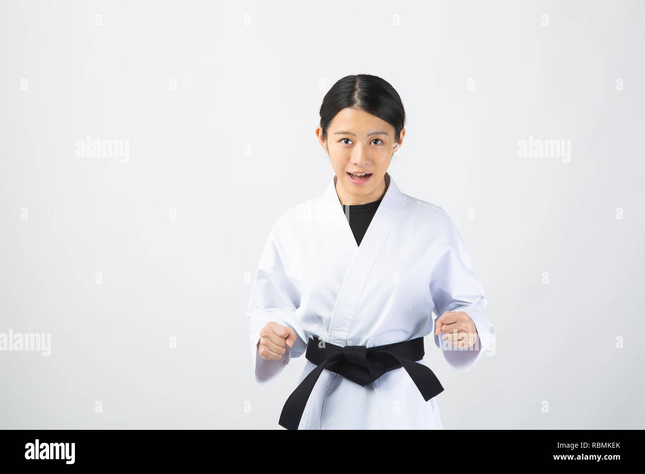 Young beautiful woman wearing karate suit performing karate on white