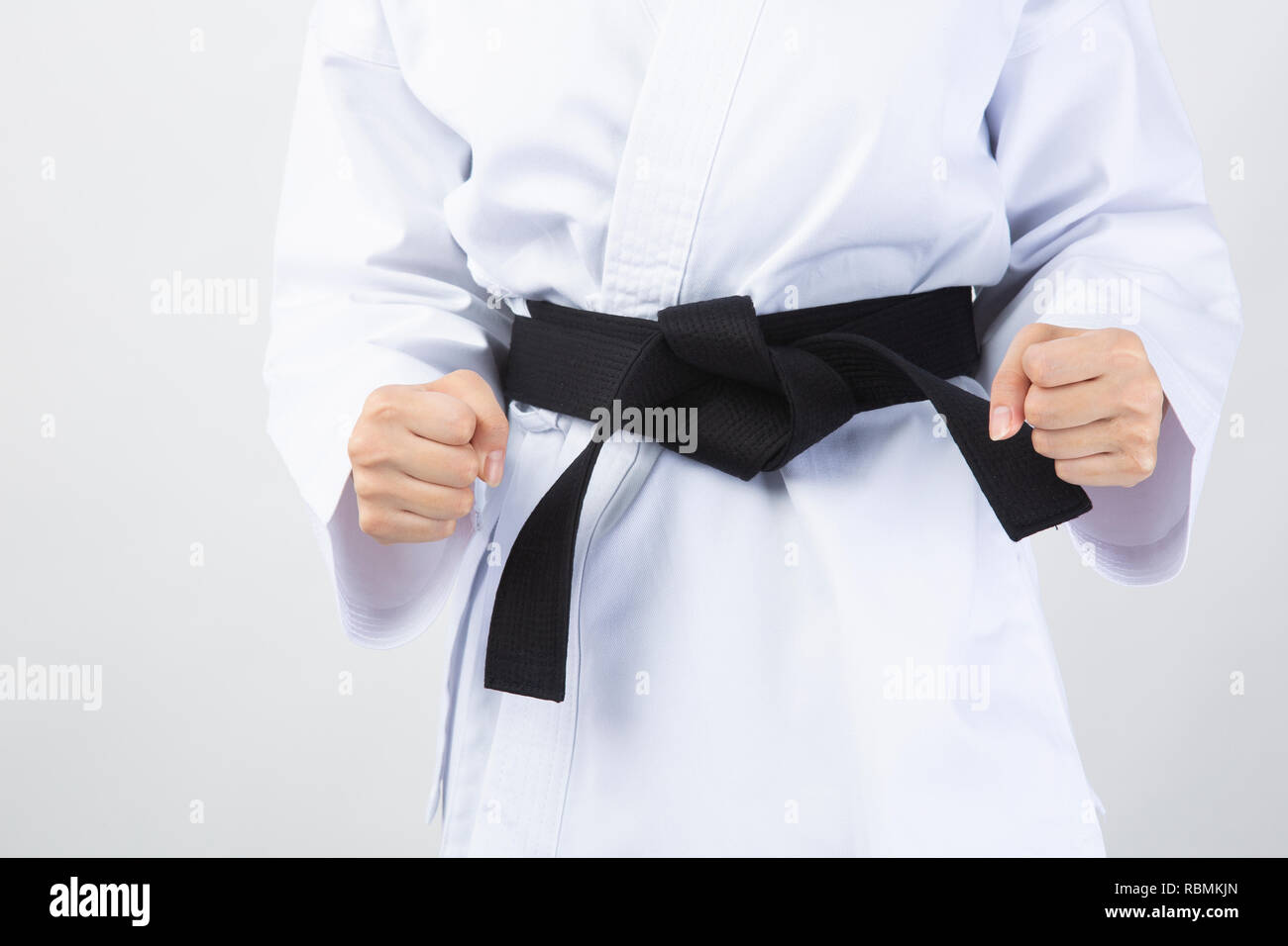 Fists of woman wearing karate suit on white background Stock Photo