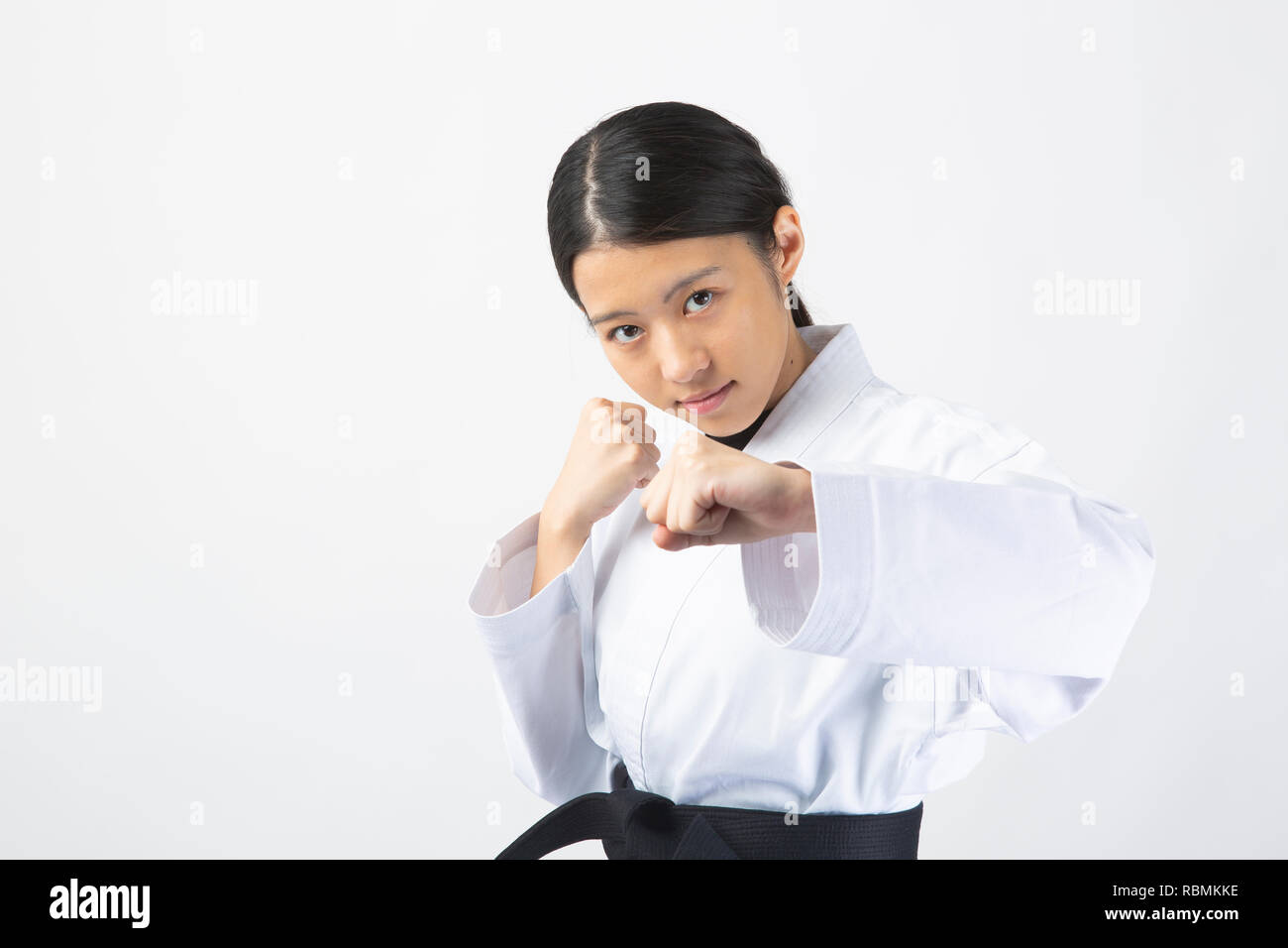Young beautiful woman wearing karate suit performing karate on white