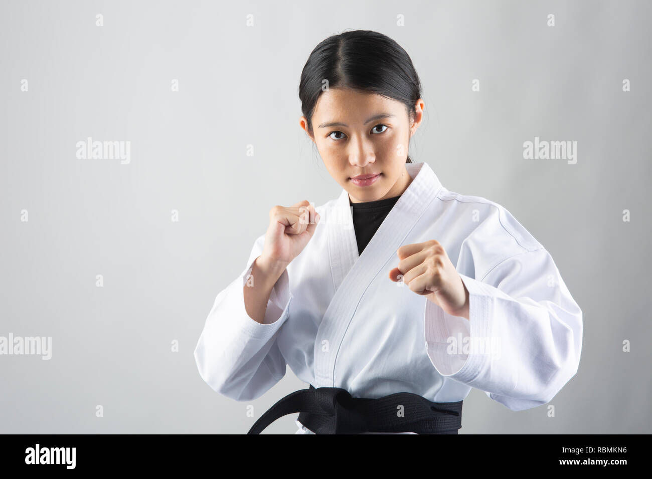 Young beautiful woman wearing karate suit performing karate on white