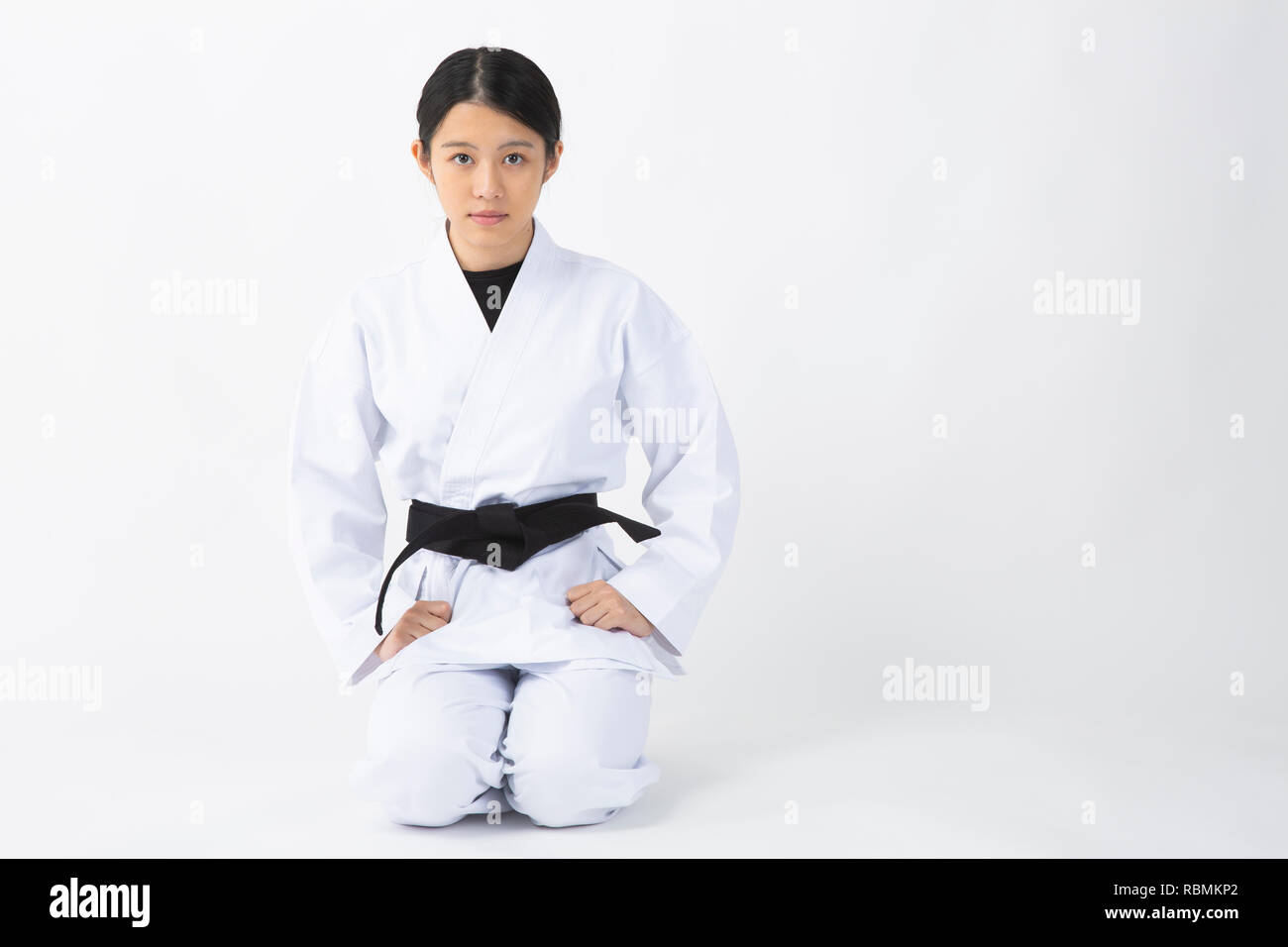 Young woman wearing karate suit staring at camera on white background Stock Photo