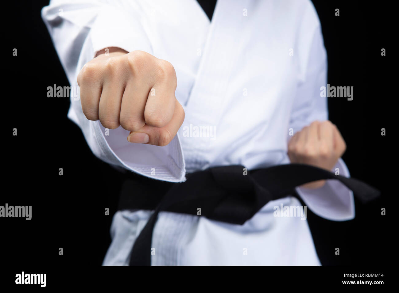 Fist of woman in karate suit on black background Stock Photo