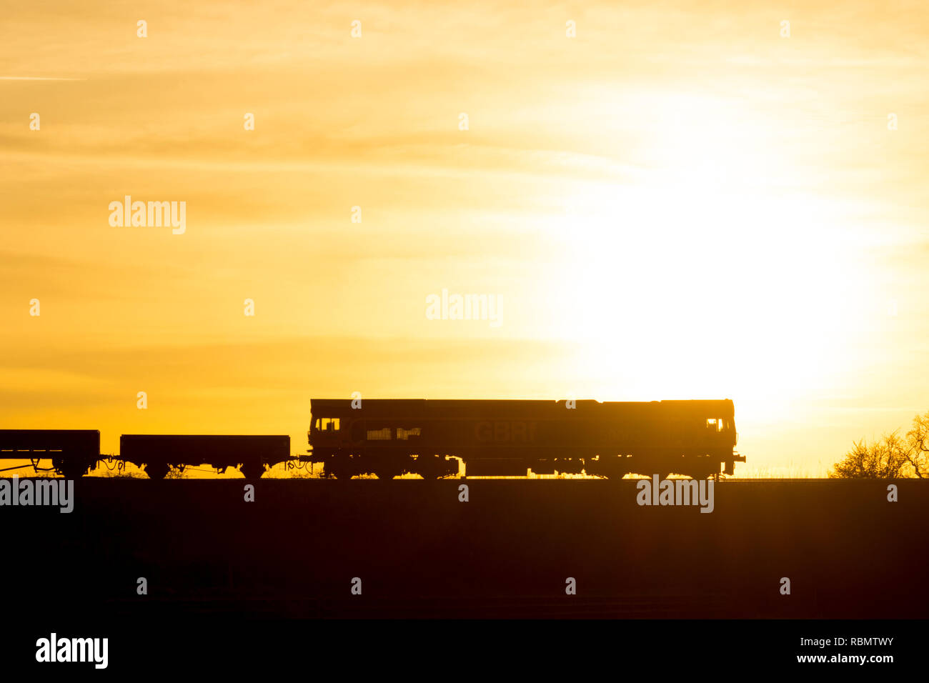 GBRf Class 59 diesel locomotive pulling a freight train, silhouetted at sunset, Warwickshire, UK Stock Photo