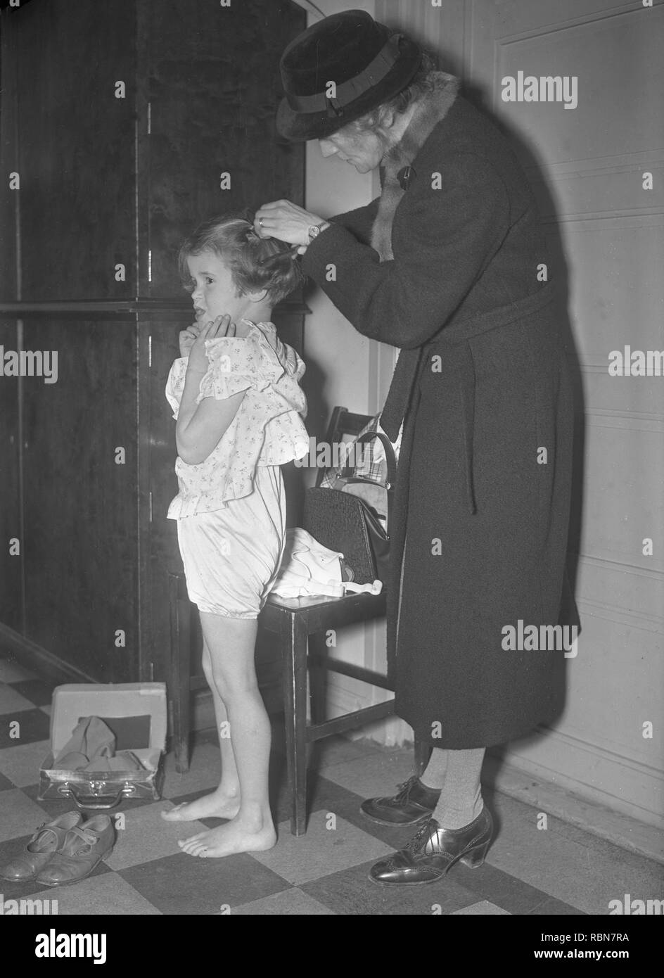 Children in the 1930s. A little girl is getting som help to put in a barrette . Photo Kristoffersson Ref 13-7. Sweden 1939 Stock Photo