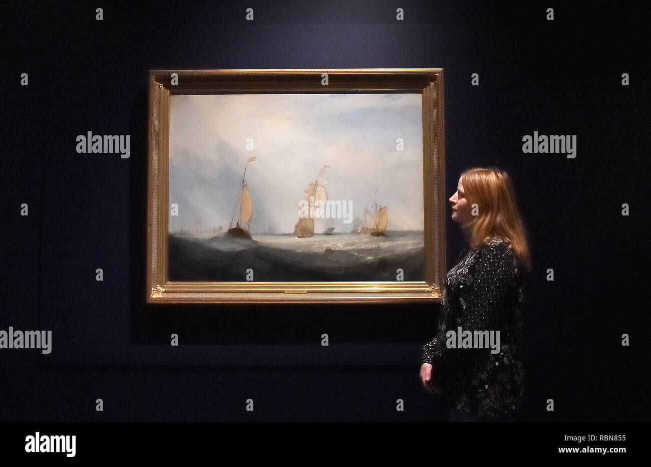 Gallery assistants with Helvoetsluys by J.M.W Turner, on display at the Royal Academy of Arts in central London for the first time since the artist clashed with John Constable at the Summer Exhibition in 1832. Stock Photo