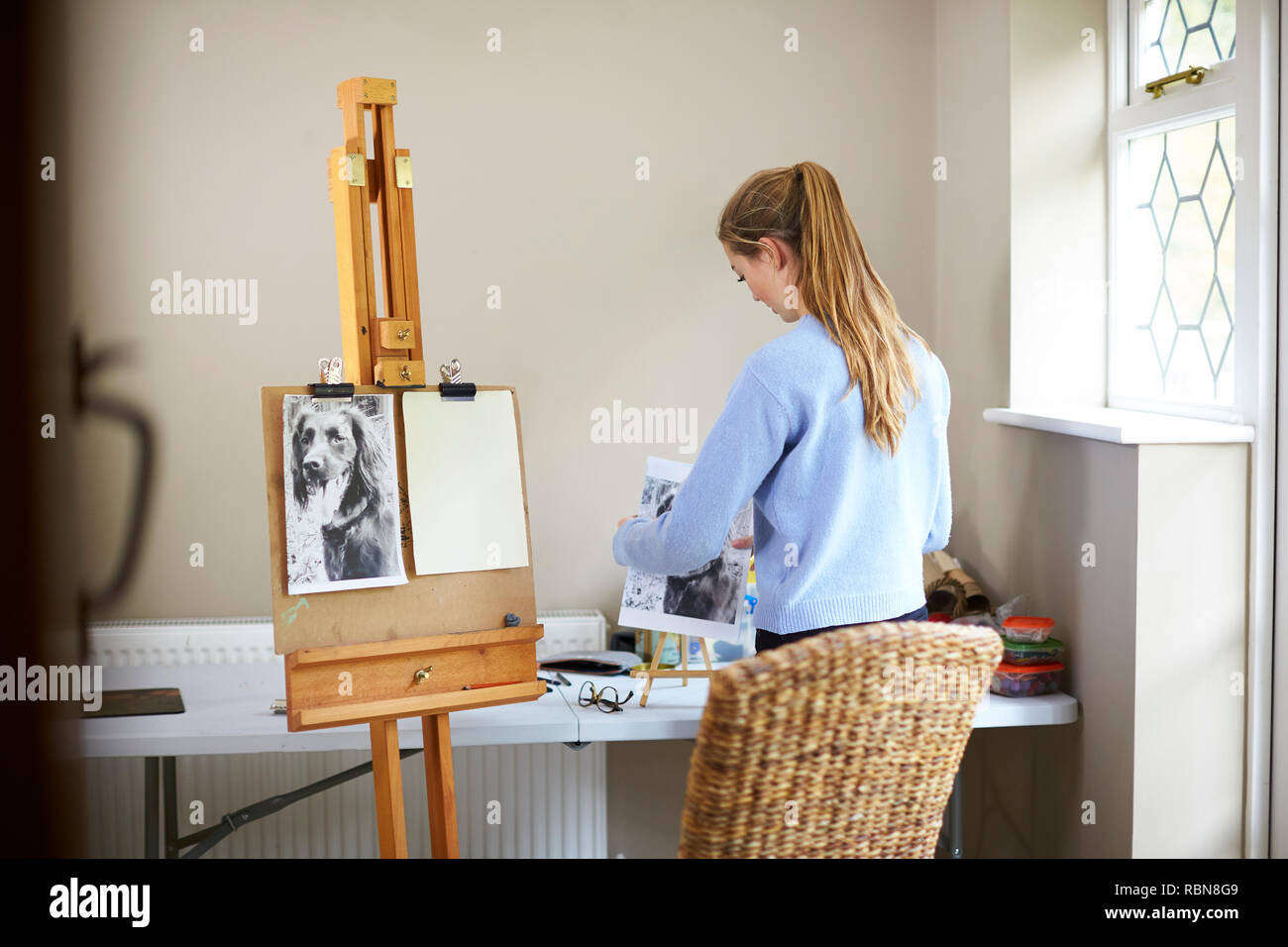 Female Teenage Artist Preparing To Draw Picture Of Dog From Photograph Stock Photo