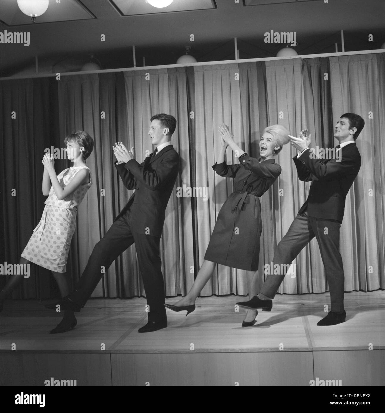 Dancing in the 1960s. The dance Hully Gully is being made popular and here are men and women dancing the new craze. Hully Gully was a type of unstructured line dance and consisted of a series of steps and was relatively simple and easy to execute. Hully Gully can be seen performed by actor John Belushi in the film Blues Brothers. Notice the typical BeeHive hairdo on the blonde girl. Stock Photo