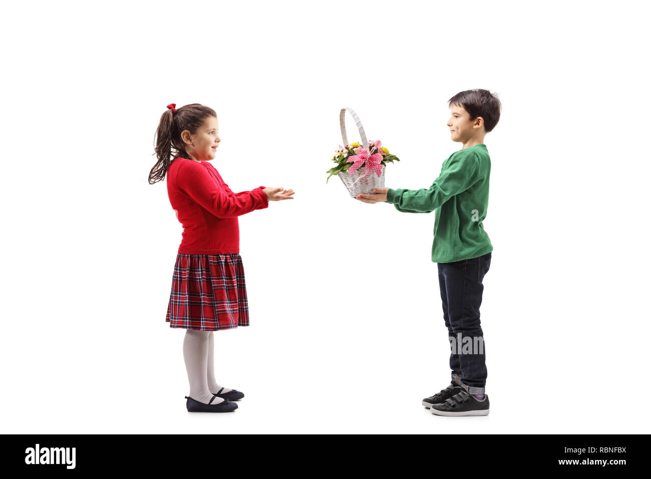 Full length shot of a little boy giving a basket with flowers to a little girl isolated on white background Stock Photo
