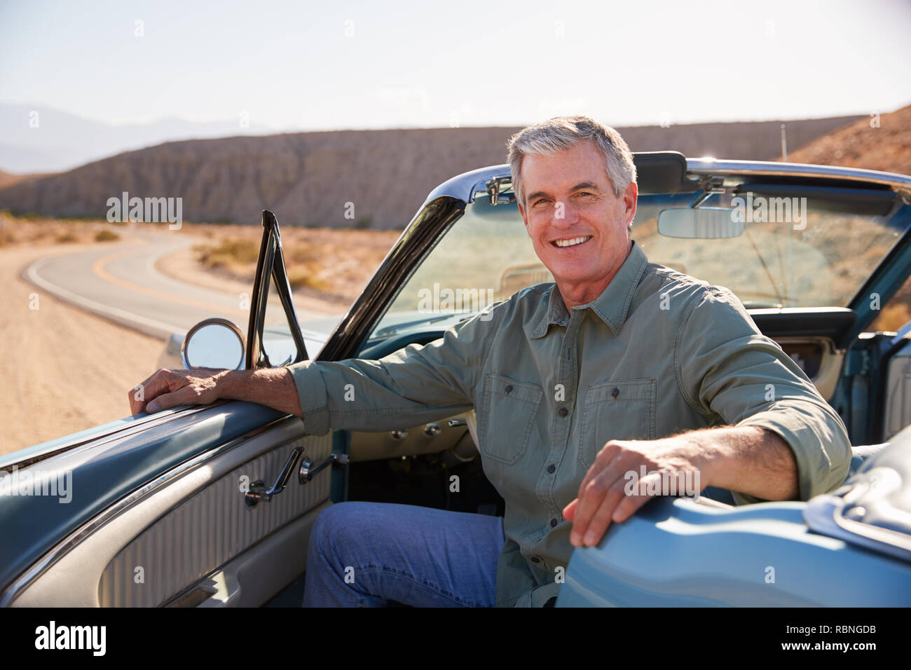 Senior man smiling to camera from parked open top car Stock Photo
