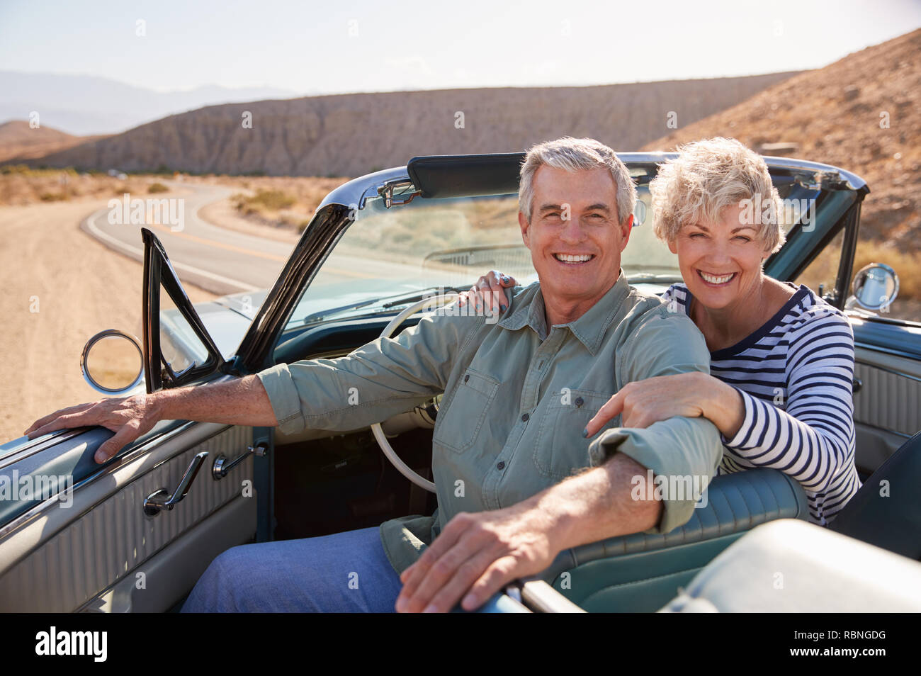 Senior couple smile to camera from open top car, close up Stock Photo