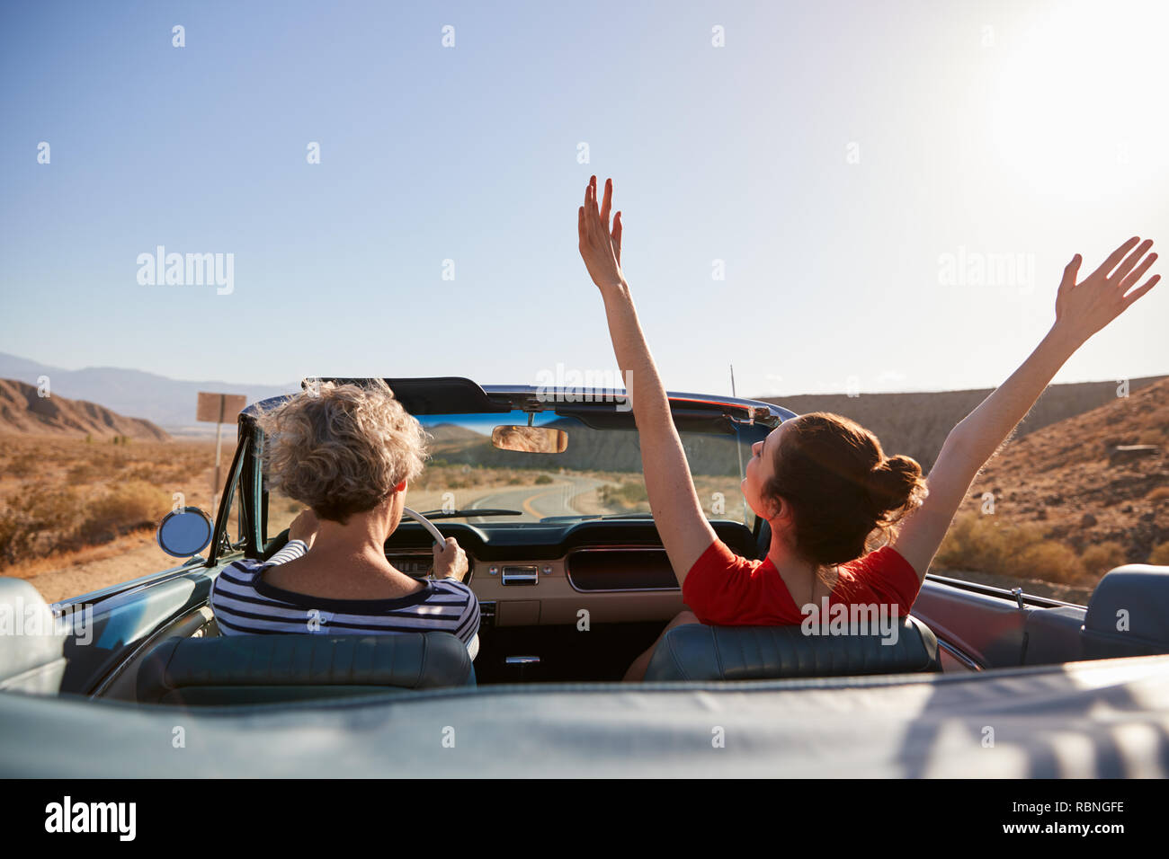 Mum driving car, daughter with hands in the air, back view Stock Photo