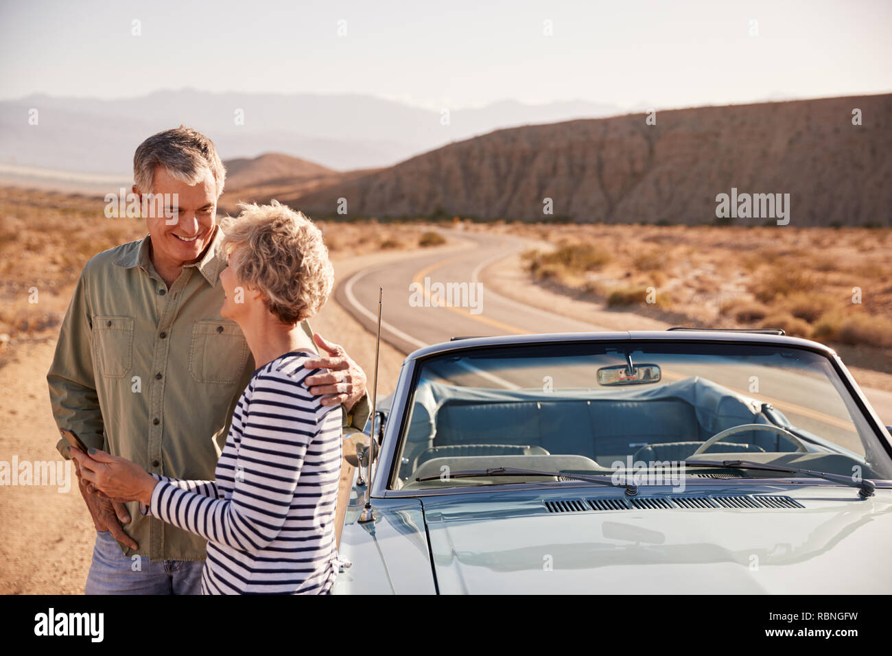 Senior couple checking map on smartphone at desert roadside Stock Photo