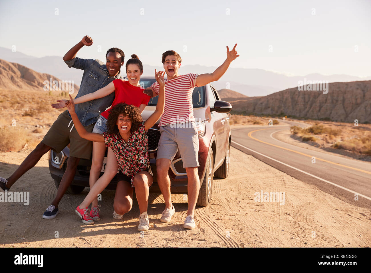 Young adult friends on road trip have fun posing by the car Stock Photo