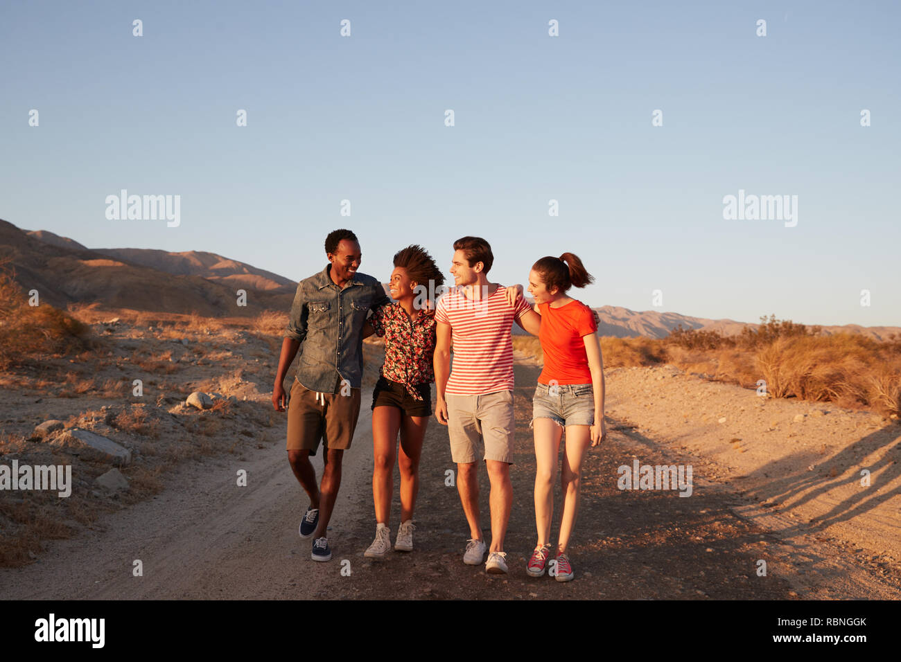 Two young adult couples walking on a desert road Stock Photo