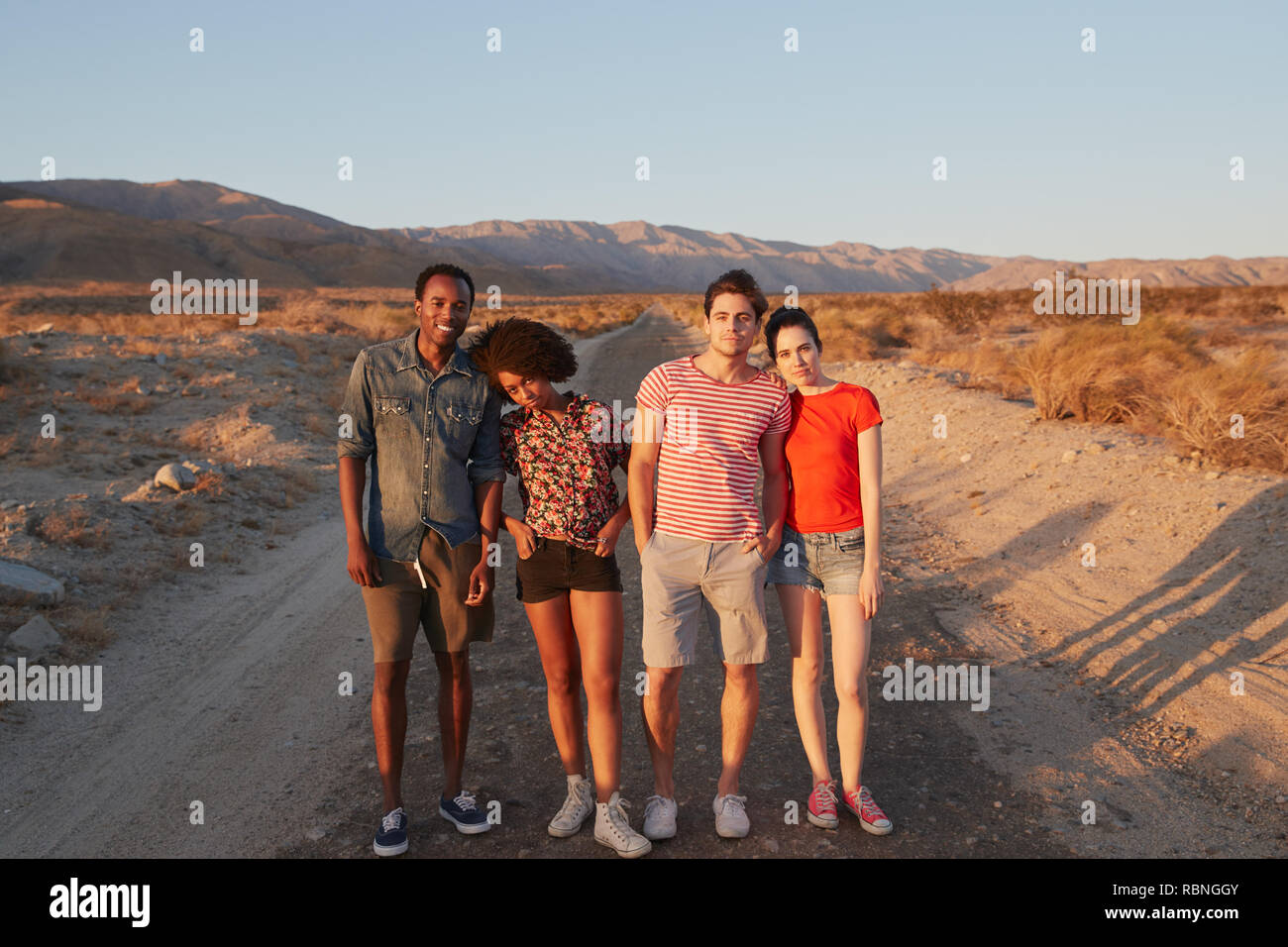 Two young adult couples on a desert road smiling to camera Stock Photo
