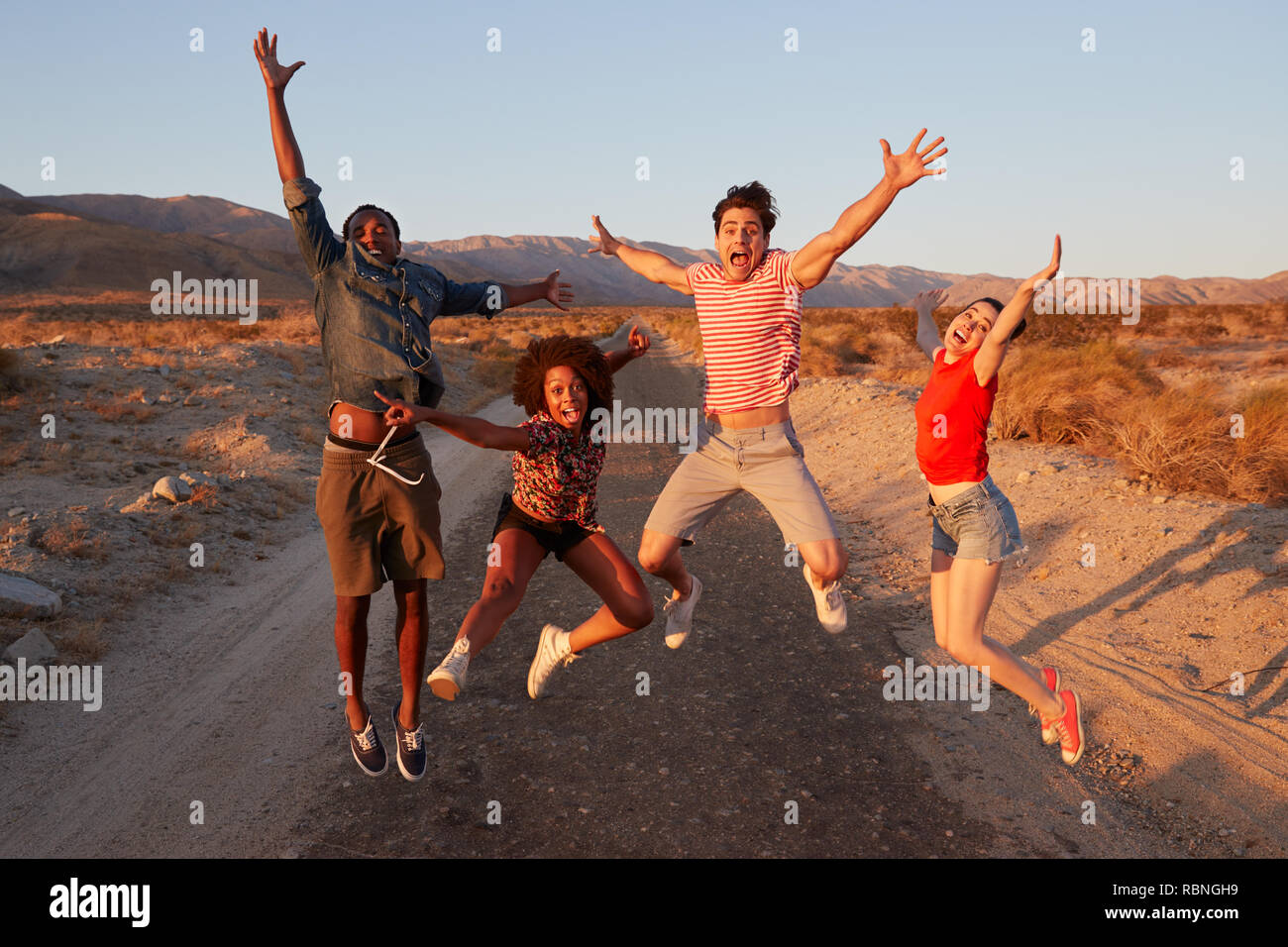 Young adult friends having fun jumping in the desert Stock Photo