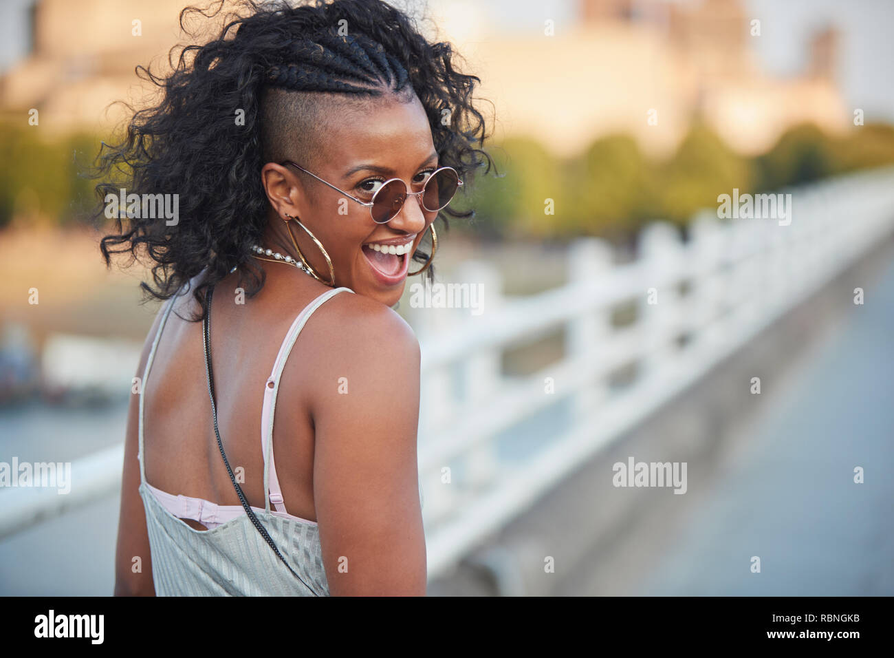 Trendy woman in striped camisole and sunglasses, turning Stock Photo