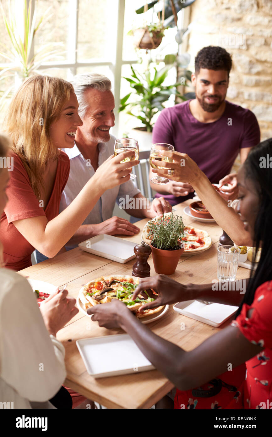 Adult friends eating in a cafe making a toast, vertical Stock Photo